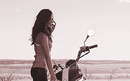 Fotografía en tonos sepia de modelo despreocupada junto a motocicleta